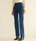 Blue jeans worn by a person on a beige background